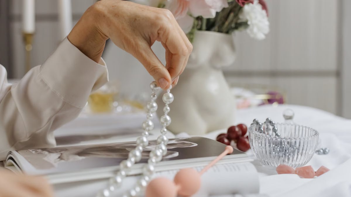 A sophisticated arrangement of pearls, flowers, and a magazine depicting elegance and grace.